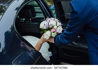 groom-helps-bride-leave-car-260nw-587767484